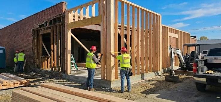 Framing crew in hard hats and safety vests raising a stud wall on a commercial job site